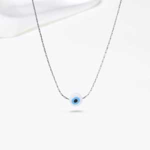 Macro detail of golden Evil Eye pendant with blue bead on minimalist chain necklace