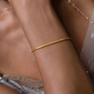 Close-up detail of a minimalist golden square snake chain bracelet on a wrist