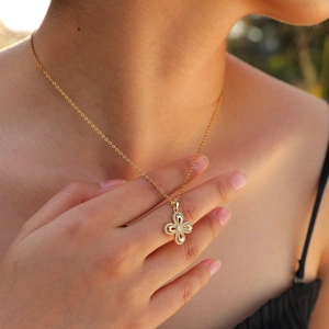 Elegant gold flower pendant necklace with white zircons worn by a female model