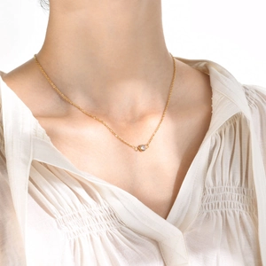 Gros plan d'un collier doré minimaliste avec un pendentif en zircon blanc sur un modèle