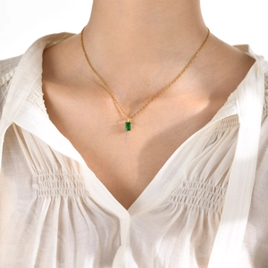 Gold stainless steel necklace featuring a rectangular emerald green zircon pendant on a model