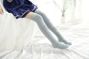 Texture détaillée de chaussettes hautes en polaire corail gris clair sur lit blanc