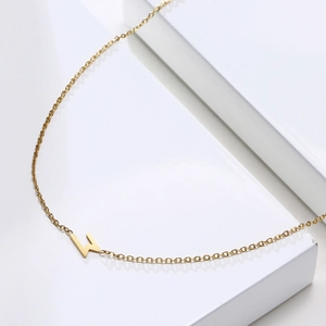 Détail macro du pendentif éclair doré sur une chaîne minimaliste en acier inoxydable