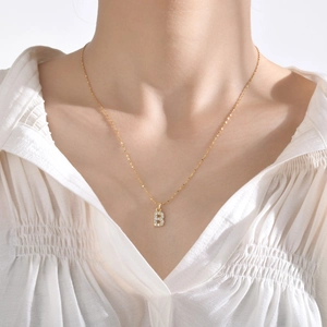 Gros plan d'un collier doré avec pendentif lettre B serti de zircons sur un mannequin