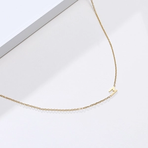 Détail du collier en acier inoxydable doré avec un pendentif lettre M au design épuré