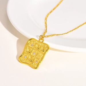 Close-up of golden square pendant with star and moon textures and cubic zirconia