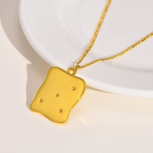 Detailed macro view of a golden cracker pendant with small white zircon stones on a thin chain