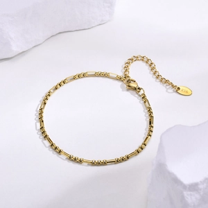 Détail du bracelet à maillons en acier doré avec poinçon K18 et fermoir sur pierre blanche