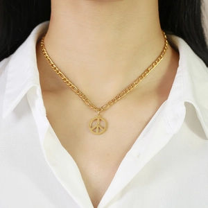 Dettaglio di una collana a catena Figaro dorata con un pendente circolare della pace