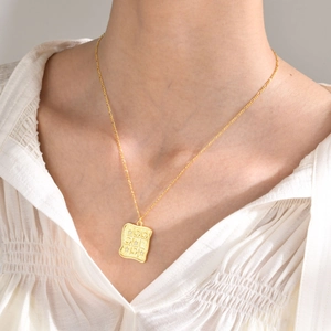 Close-up of gold square grid necklace with zircon details on a model wearing white chiffon