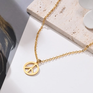 Dettaglio della collana con pendente segno della pace dorato su pietra decorativa e sfondo