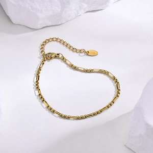 Détail d'un bracelet chaîne en or 18 carats avec fermoir homard sur fond de pierre blanche
