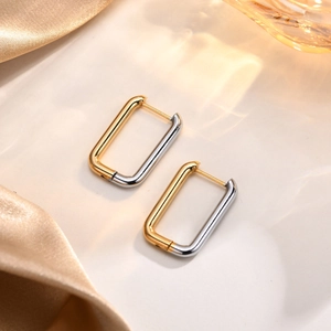 Close-up of geometric U-shaped rectangular earrings with gold and silver color block finish