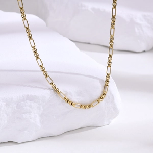 Détail macro d'un collier en acier doré avec maillons rectangulaires et perles