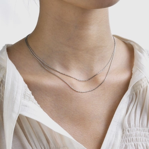 Macro view of dainty silver double-layered chain necklace worn on a woman's collarbone