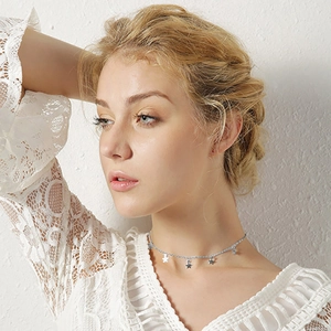 Détail d'un collier en acier inoxydable argenté avec pendentifs étoiles porté par un mannequin