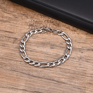 Gros plan d'un bracelet Figaro en acier inoxydable poli avec fermoir mousqueton sur bois