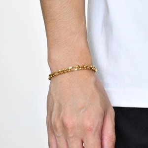 Gros plan d'un bracelet gourmette Figaro doré pour homme avec fermoir mousqueton