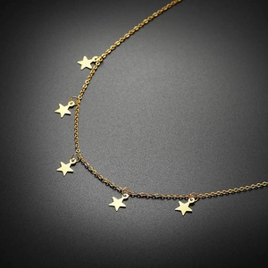 Détail d'un collier en acier inoxydable doré avec cinq charms étoiles polis sur fond noir