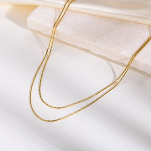 Detail of double-layer golden hammer circle chain on silk and marble background