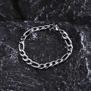 Détail du bracelet chaîne Figaro argenté avec fermoir mousqueton sur fond de roche