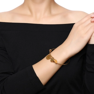 Bracelet ajustable en acier titane doré avec pendentifs cœur sur un poignet