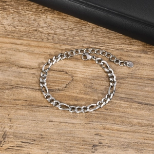 Gros plan d'un bracelet gourmette Figaro classique en argent sur une surface en bois