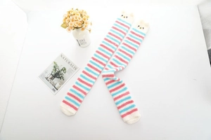 Détail de chaussettes hautes rayées en polaire corail avec pompons en peluche