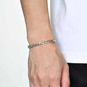 Gros plan d'un bracelet maille Figaro en acier inoxydable poli sur poignet homme