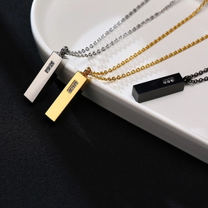 Macro detail of three vertical zircons on sleek bar pendant in gold, silver, and black