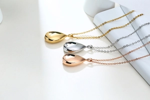 Polished teardrop cremation pendants in gold, silver, and rose gold on white display