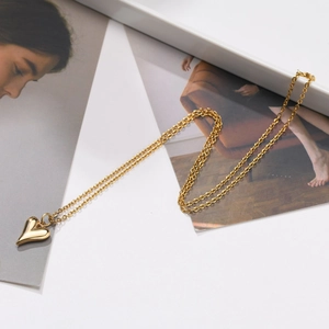 Détail d'un collier pendentif cœur doré poli posé sur un magazine de mode élégant
