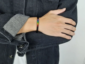 Close-up of matte black stainless steel cuff bracelet featuring a vibrant rainbow enamel strip