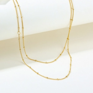 Macro detail of a 2mm gold stainless steel bead chain necklace with polished finish