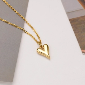 Collier avec pendentif coeur doré poli sur un fond moderne minimaliste gris et blanc