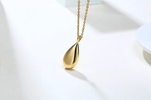Detailed macro view of gold-toned teardrop cremation urn pendant with mirror polish finish