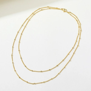 Detail of double-layer gold snake chain necklace with small beads and lobster clasp
