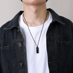 Male model wearing a minimalist black stainless steel bar pendant necklace over a white t-shirt