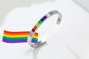 Macro shot of polished stainless steel C-shaped cuff with rainbow enamel inlay squares
