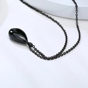 Macro shot of a glossy black teardrop urn pendant with a polished mirror finish on a chain