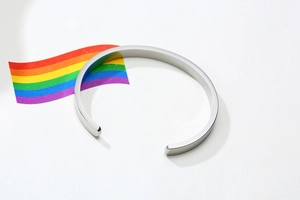 Close-up of silver stainless steel C-shaped cuff bracelet with a vibrant rainbow pride card