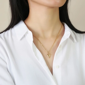 Collier élégant avec pendentif cœur doré sur un mannequin portant une chemise blanche