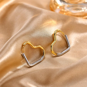 Detailed shot of two-tone heart earrings in gold and silver on silk fabric