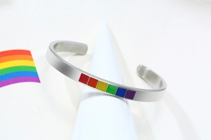 Macro detail of C-shaped stainless steel bangle featuring colorful rainbow enamel squares