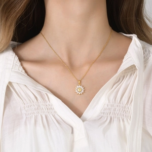 Detalle de un collar de girasol dorado con pétalos de gemas sobre una blusa blanca