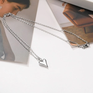 Détail du pendentif en forme de cœur sur une fine chaîne avec fermoir mousqueton sur fond blanc