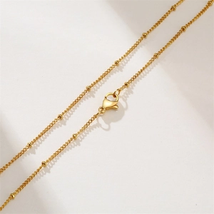 Detail of 2mm gold satellite chain necklace featuring solid beads and a lobster clasp