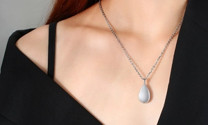 Close-up of polished silver teardrop urn pendant necklace on model's neck