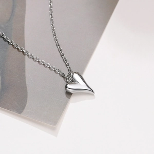 Détail macro d'un pendentif coeur minimaliste avec finition miroir et chaîne fine