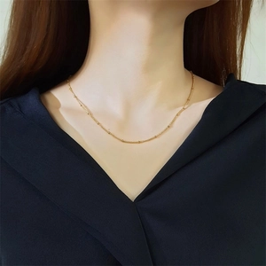 Detail shot of a delicate 2mm gold beaded snake chain necklace worn on a female model